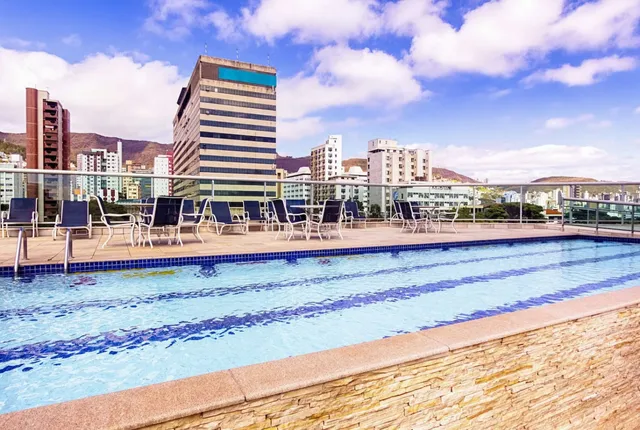 Apartamento moderno com varanda e vista para ruas arborizadas de BH ao entardecer