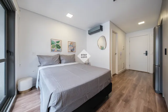 Quarto de temporada recém-montado com cama queen, roupa de cama branca e abajur
