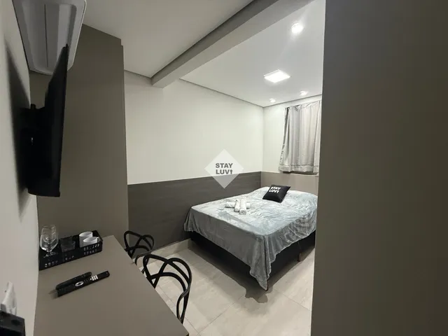 Cama de casal arrumada com lençóis brancos e almofadas em apartamento de temporada