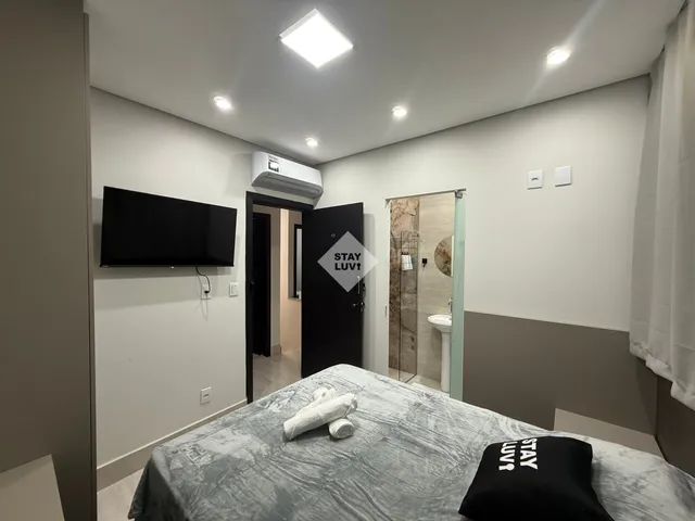 Sala de apartamento decorada com sofá claro, plantas e iluminação quente
