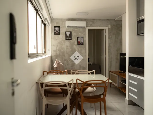Sala de apartamento studio com sofá compacto, mesa e cozinha integrada