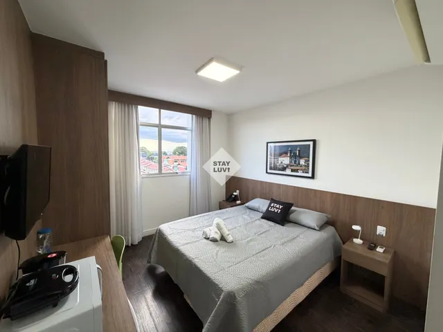 Escrivaninha em apartamento com notebook, luminária e vista para janela