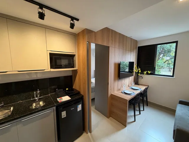 Studio moderno com cozinha integrada, cama e área de trabalho em espaço compacto