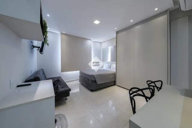 Apartamento com decoração sóbria, mesa de trabalho com laptop e janela com vista para a cidade